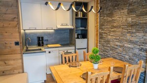 A compact kitchen with white cabinets, a built-in oven, and a stone wall. - 150m from ski slopes, 7th floor, view terrace, swimming pool, sauna, terrace, balcony, ski locker (Les Orres)