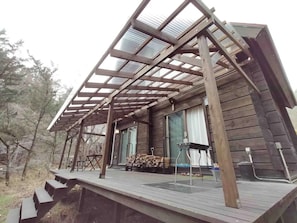A wooden cabin with a covered porch, a fireplace, and a stack of firewood outside.
