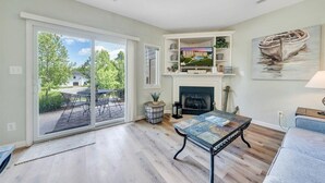 A spacious living room with a fireplace, a television, and a painting of a boat on a lake. - MV70 - 2 Bedroom condo at Mariners SML (Huddleston)