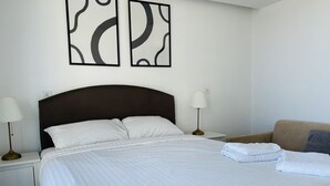 Una cama con ropa de cama blanca impecable, un cabecero oscuro y dos lámparas de noche.