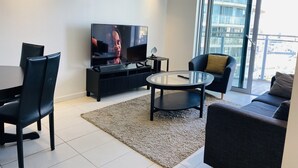 Una sala de estar moderna con televisor de pantalla plana, una mesa de comedor y sillas.