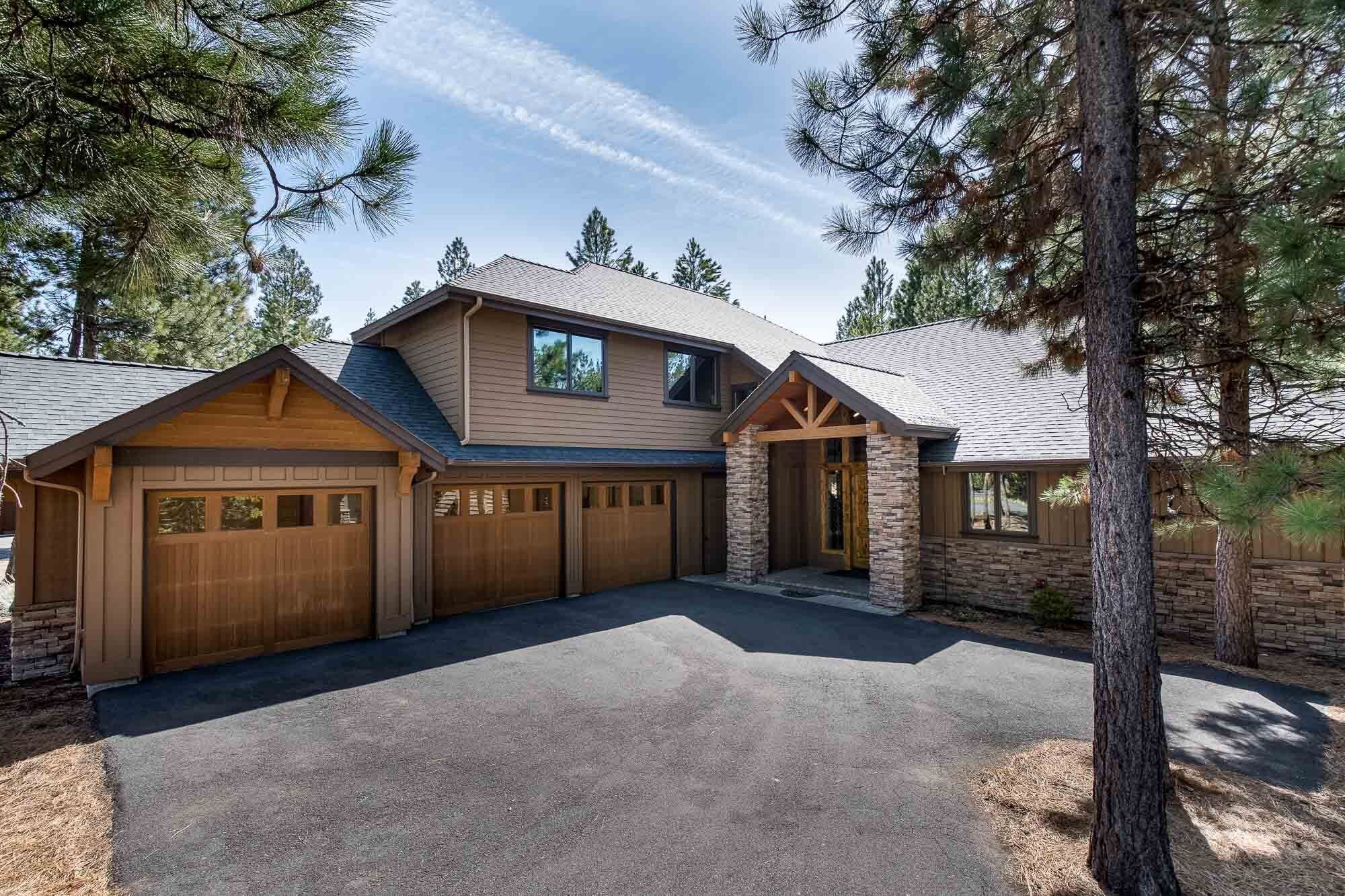 A two-story house with a stone foundation, a garage with wooden doors, and a covered entryway.