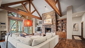 Amplia sala de estar con un sofá modular grande, chimenea, vigas de madera y una pared de acento de piedra.