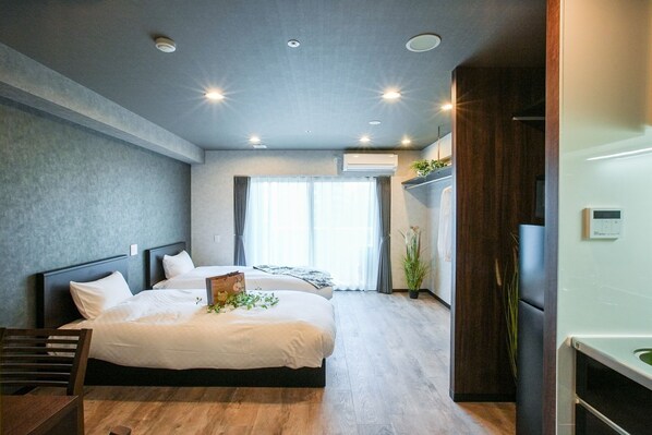 A modern bedroom with two beds, a wooden floor, and an air conditioning unit.