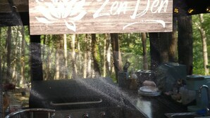 Ein hölzernes Schild mit einer Lotusblume und dem Schriftzug "The Zen Den" unter einer Konstruktion.