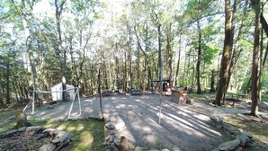 Ein Campingplatz mit Volleyballnetz, Picknicktischen und einer kleinen Schutzhütte.