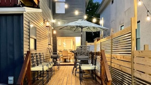 A wooden deck with outdoor furniture, string lights, and a covered patio area.
