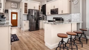 A modern kitchen with white cabinets, stainless steel appliances, and a central island with bar stools.