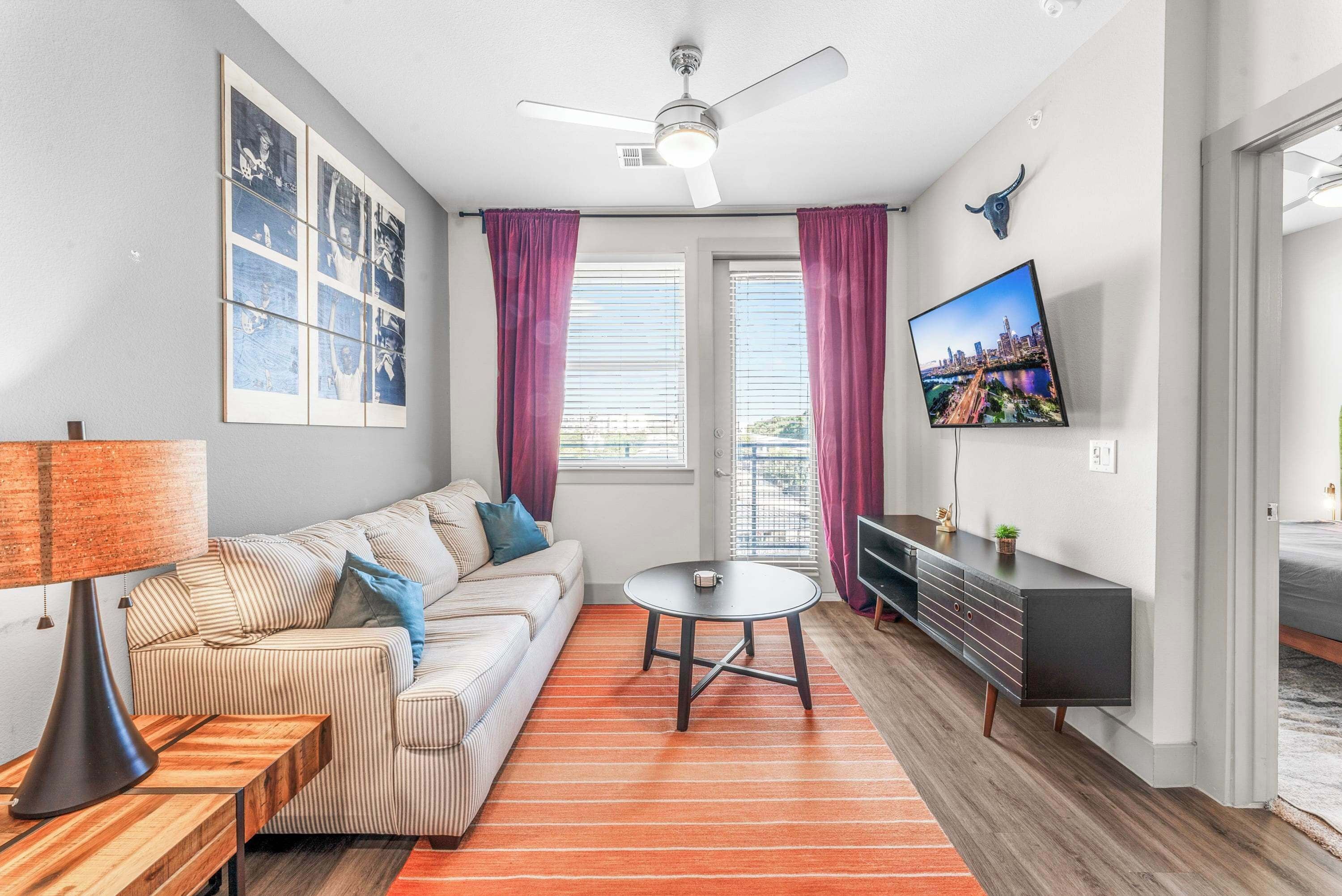 A modern living room with a sofa, a coffee table, a TV, and a ceiling fan.