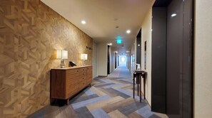 Stylish corridor with a patterned wall, wooden reception desk, and geometric tile floor.