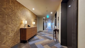 Stylish corridor with a patterned wall, wooden reception desk, and geometric tile floor.