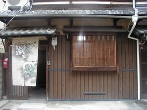 Un edificio japonés tradicional con puerta de madera, pequeña entrada y adorno colgante.
