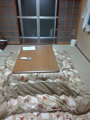 Una habitación con una cama, una mesa de madera y un ventanal corredero.