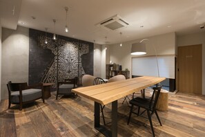 Una sala riunioni moderna con un tavolo in legno, due sedie, una parete decorata e un bocchettone di ventilazione al soffitto.