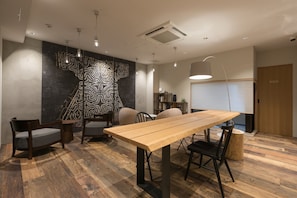 Una sala riunioni moderna con un tavolo in legno, due sedie, una parete decorata e un bocchettone di ventilazione al soffitto.