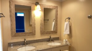 A bathroom with two sinks, a mirror, and a towel rack.