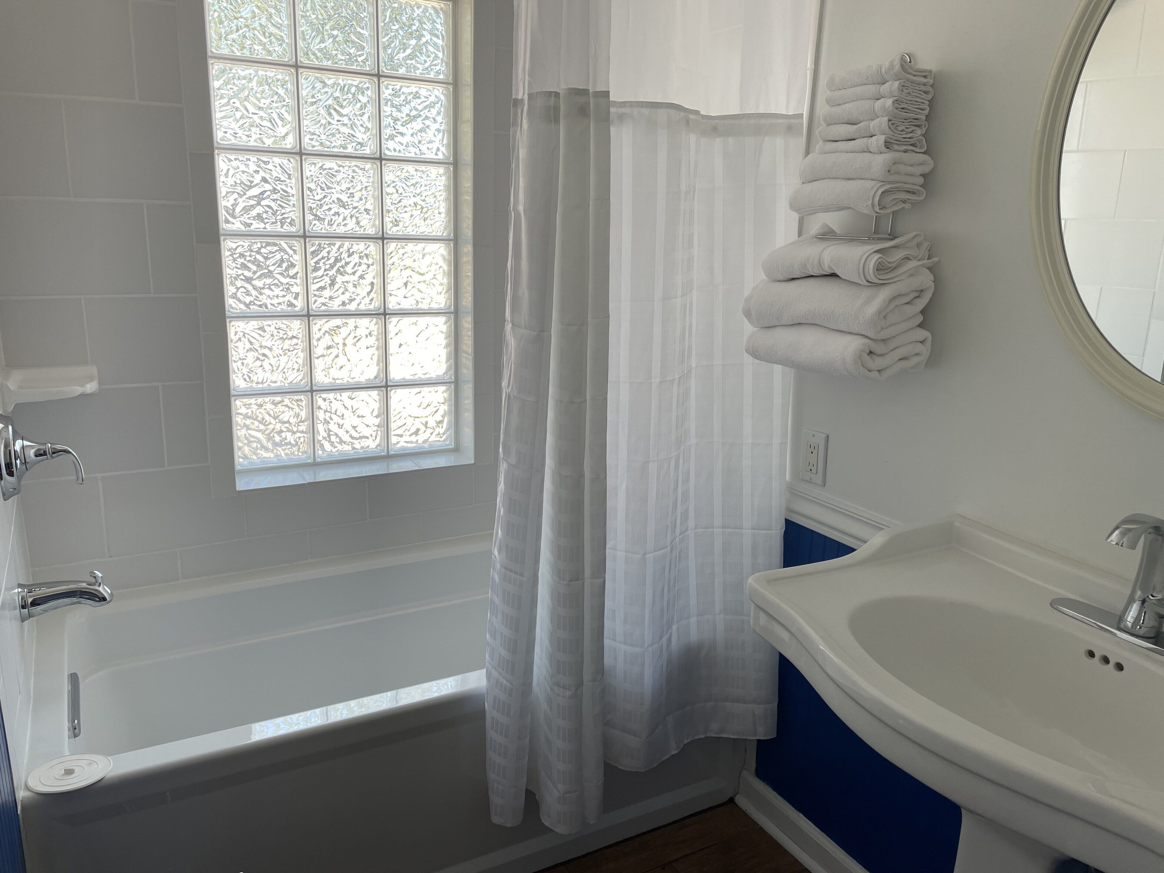 Un bagno con vasca, lavandino e finestra con pannelli di vetro satinato.