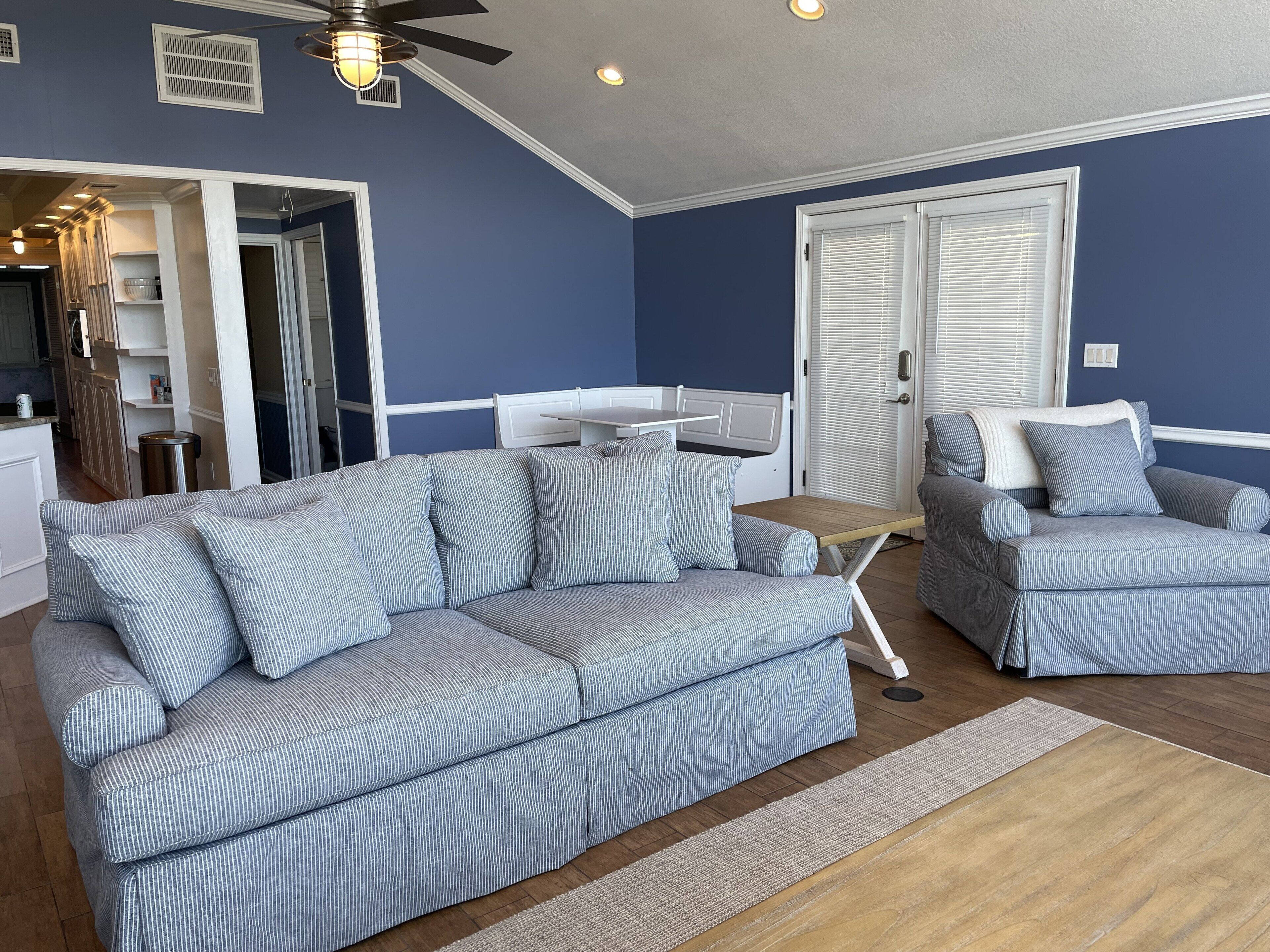 Una sala de estar con un sofá modular, un sillón, una mesita y una puerta.