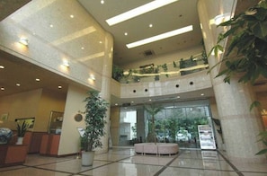Welcome to our lobby, featuring a high ceiling, modern lighting, and lush greenery.