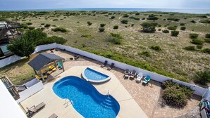 Uma área de piscina com hidromassagem, espreguiçadeiras e vista para a praia.