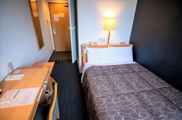 A hotel room with a bed, a desk, and a nightstand with a lamp. - Semidouble room Smoking allowed Narrow double / Handa Aichi (Handa)