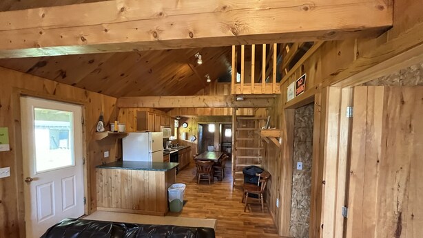 Interno di una baita in legno con cucina, zona pranzo e soggiorno con divano in pelle.