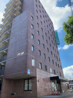 Hotel features a striking brick and glass facade with balconies and a welcoming entrance.