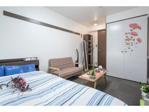 Quarto de hotel com cama, sofá, uma mesa pequena, um espelho e um guarda-roupa.