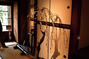 Une pièce de style japonais traditionnel, avec un sol recouvert de tatamis, une petite table en bois et une plante suspendue.