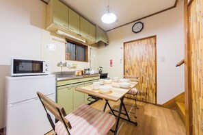 A compact kitchen with a microwave, stove, and wooden dining table with chairs.