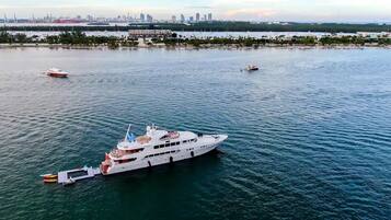 A large yacht docked at a marina with a city skyline in the background.