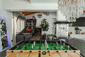 Una habitación con mesa de futbolín, mesa de billar y una máquina Lincoln Popper.