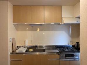 A compact kitchen with wooden cabinets, a stainless steel sink, and a gas stove. - Yokohama design room 7min from Yokohama station - Room 305 / Yokohama Kanagawa (Yokohama)