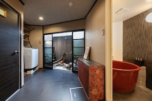 A modern bathroom with a red bathtub, a wooden vanity, and a large window with a view of the outdoors.