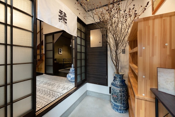 A traditional Japanese interior with sliding doors, a wooden reception desk, and a large blue vase.
