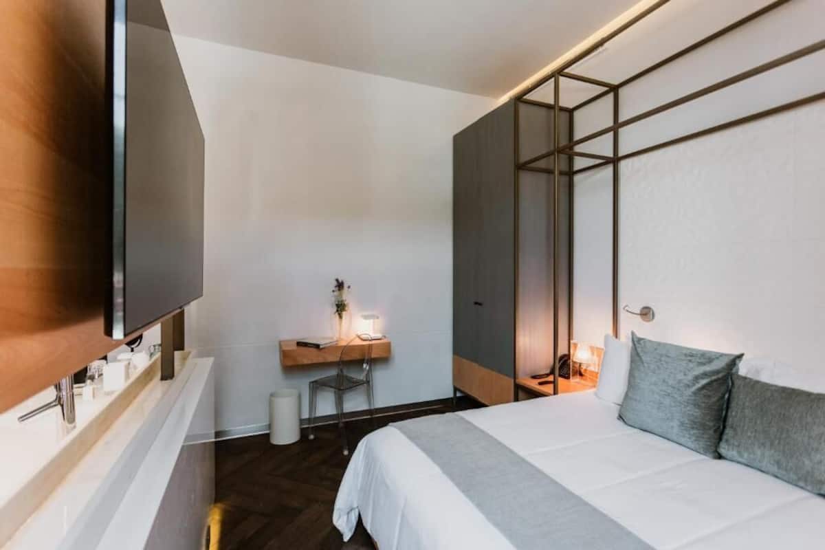 Une chambre d’hôtel moderne dotée d’un grand lit, d’un bureau avec une chaise, d’un téléviseur fixé au mur et d’une armoire.