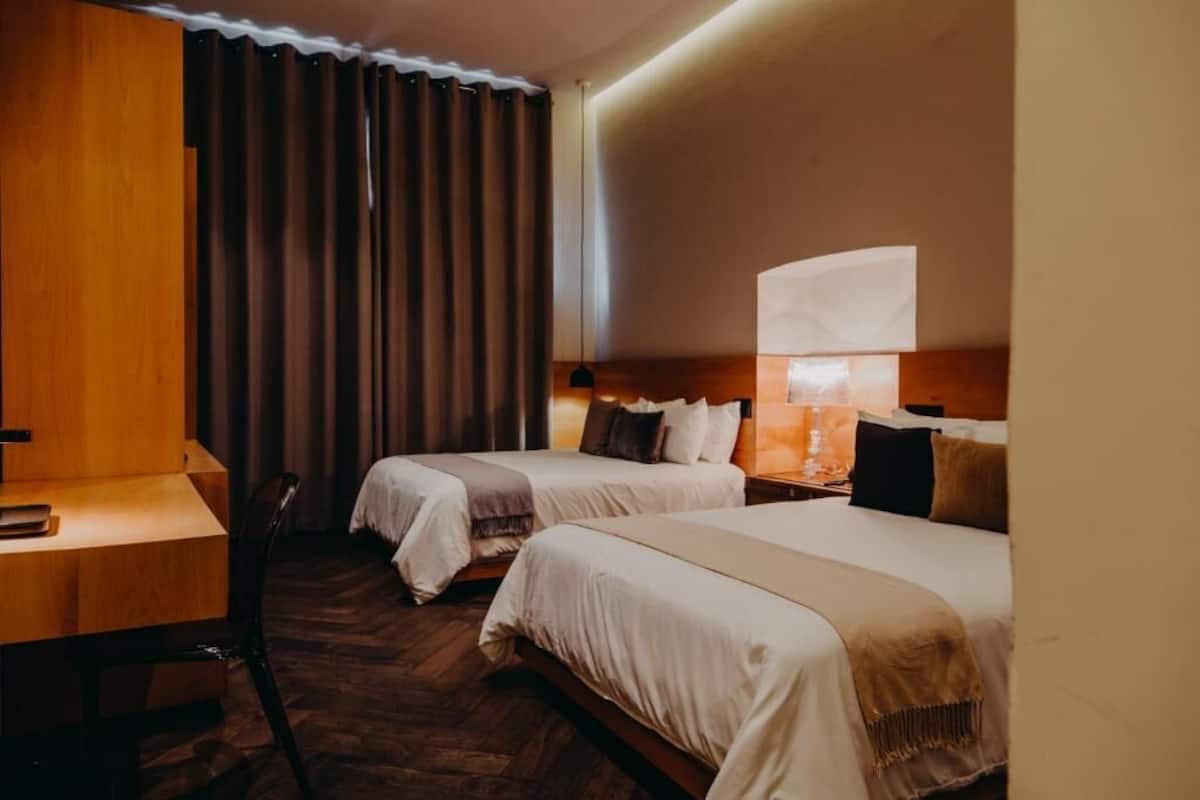 Une chambre d’hôtel avec deux lits, un bureau et une chaise.