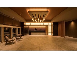 Un'ampia hall con reception, area lounge e un moderno lampadario.