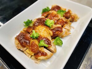 Un plato de pollo en rodajas con salsa brillante y brócoli.