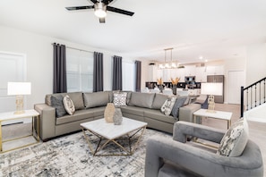 A modern living room with a sectional sofa, a coffee table, and a grey armchair.