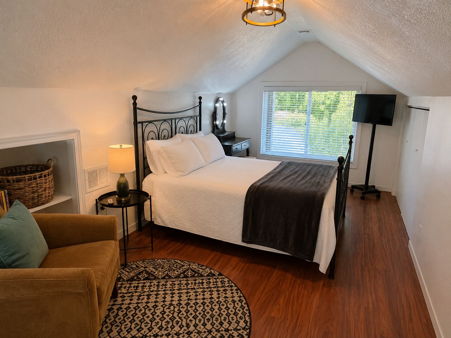 A bedroom with a bed, bedside lamp, window, and a lamp on a stand.