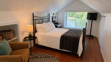 A bedroom with a bed, bedside lamp, window, and a lamp on a stand.