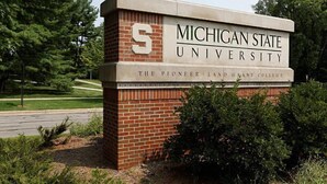 A sign for Michigan State University, The Pioneer Land Grant College, with a brick base and a white top.