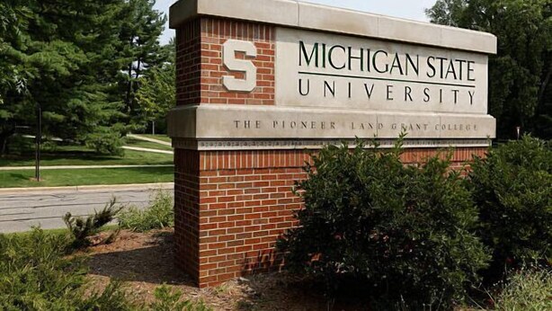 Ein Schild für die Michigan State University, The Pioneer Land Grant College, mit rotem Sockel und weißer Oberseite.