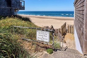 A beach access sign indicating private beach access with no trespassing, Surftides Plaza, and romantic retreats.