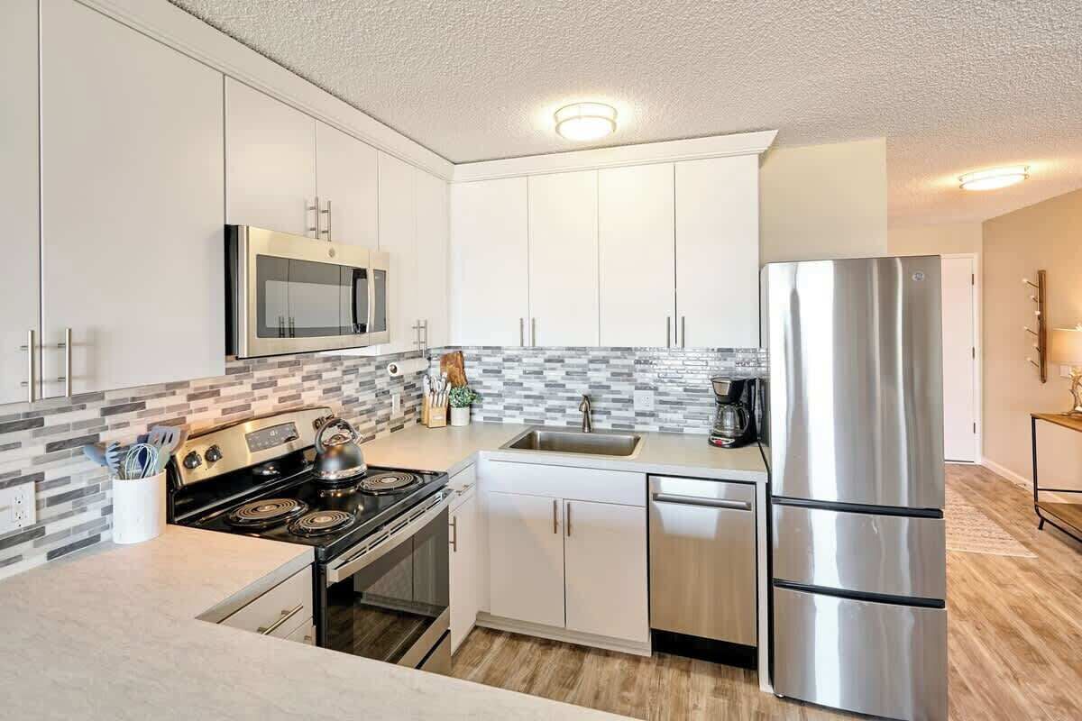 A modern kitchen with white cabinets, stainless steel appliances, a microwave, and a refrigerator.
