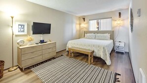 A bedroom with a bed, bedside table, lamp, TV, and a dresser. - Ocean View Condo - Second Floor - Pet Friendly! (Lincoln City)
