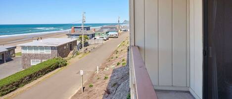 Un balcón con vista a la playa, un estacionamiento y un edificio con una puerta.