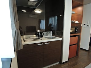 Una kitchenette compacta con lavamanos, cafetera y microondas.