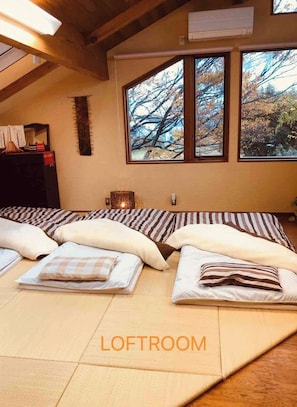 Relax in this serene loft bedroom with a high ceiling, exposed beams, and a large bed.
